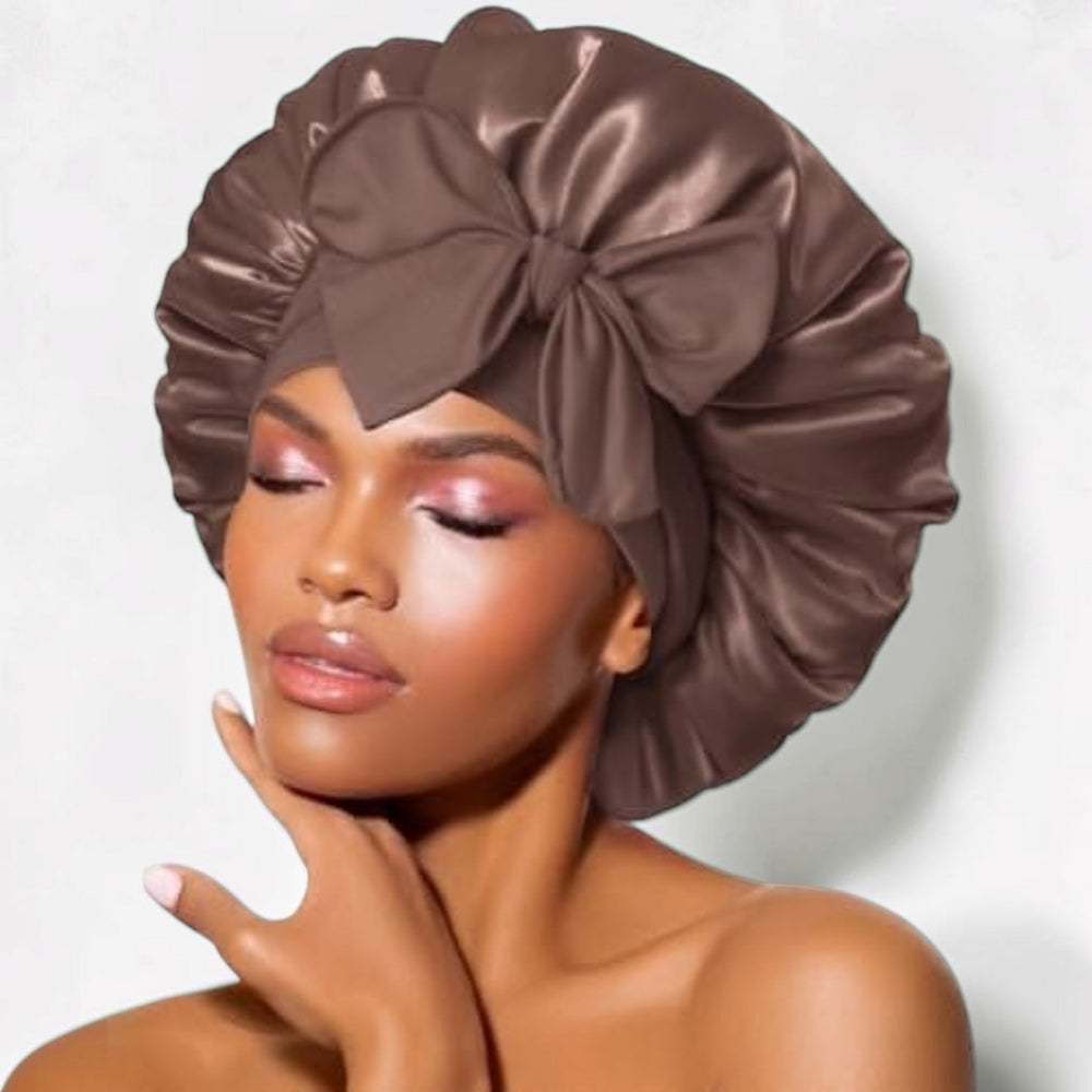 Brown satin sleep bonnet with wide adjustable tie band and front bow, worn by woman