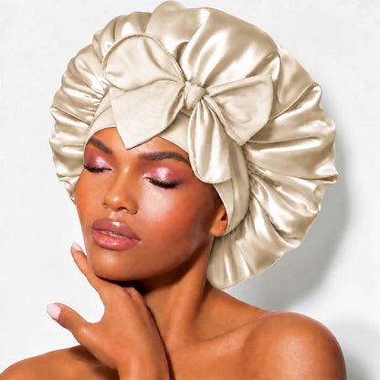 Champagne satin sleep bonnet with wide adjustable tie band and front bow, worn by woman